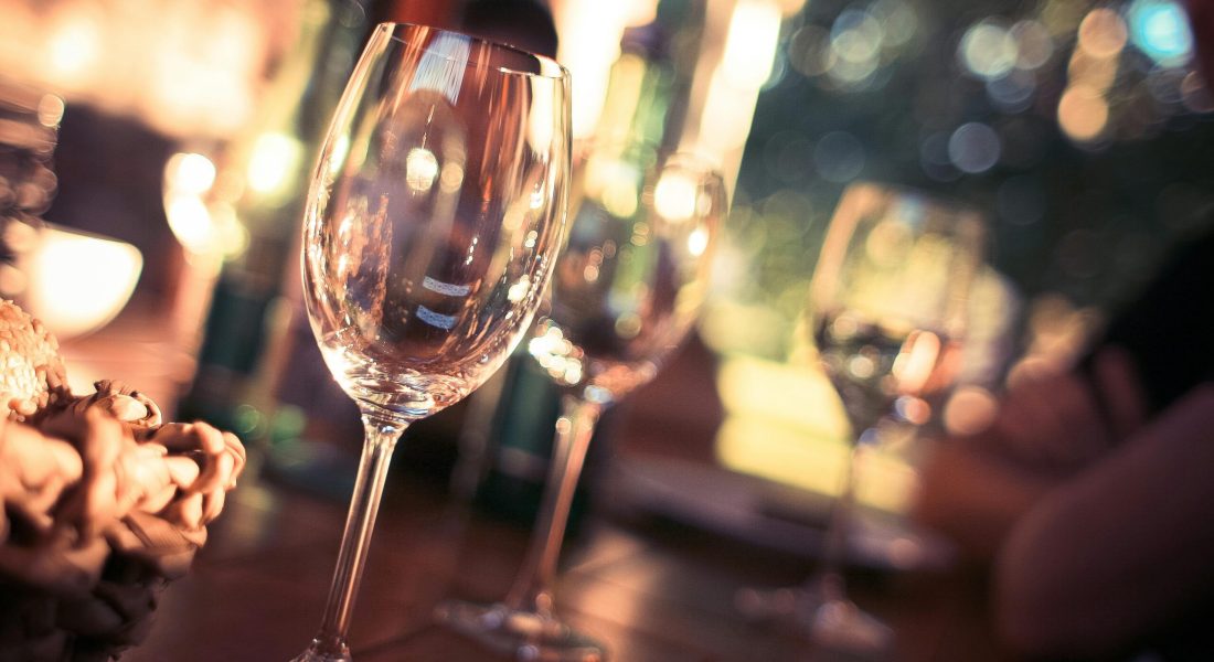 Close-up of wine glasses on a dining table with bokeh lights, creating a warm and inviting atmosphere.